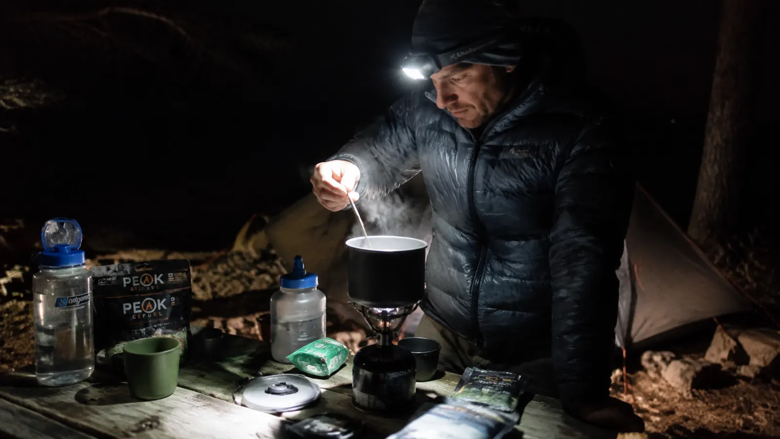 Morning coffee at camp with a headlamp resting on the picnic table beside a mug