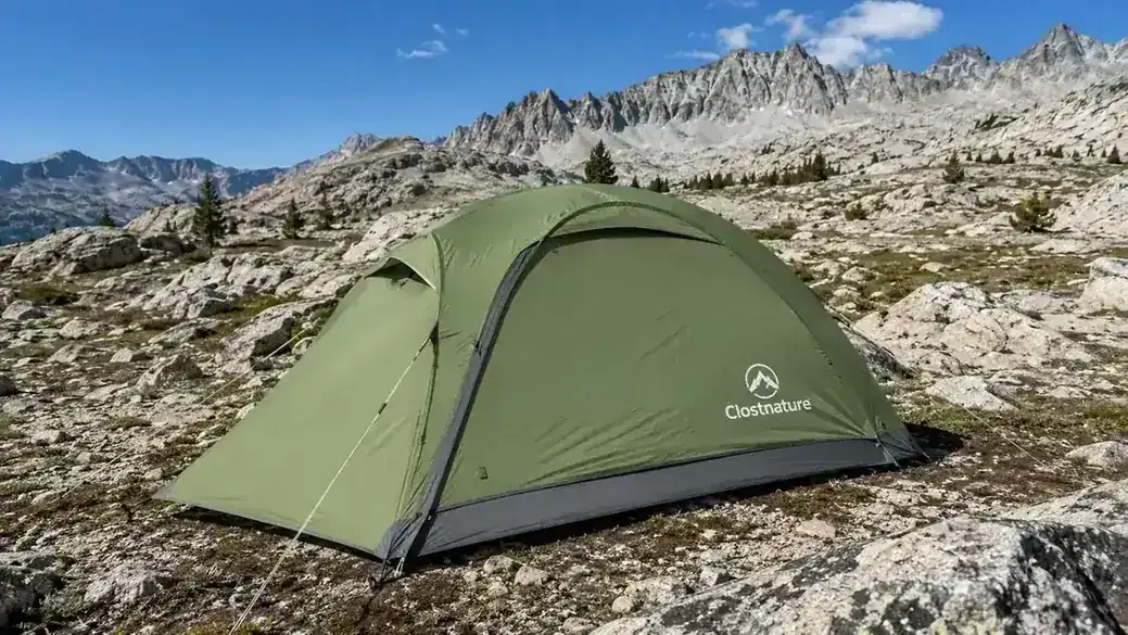 Clostnature backpacking tent pitched on a rocky alpine meadow with trekking poles stacked nearby